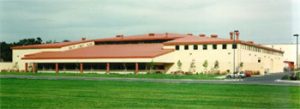 A large building with a sloped roof with a field in front.
